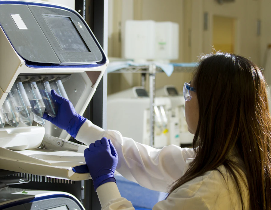 Diagnostka w rękawiczkach obsługuje analizator w laboratorium medycznym